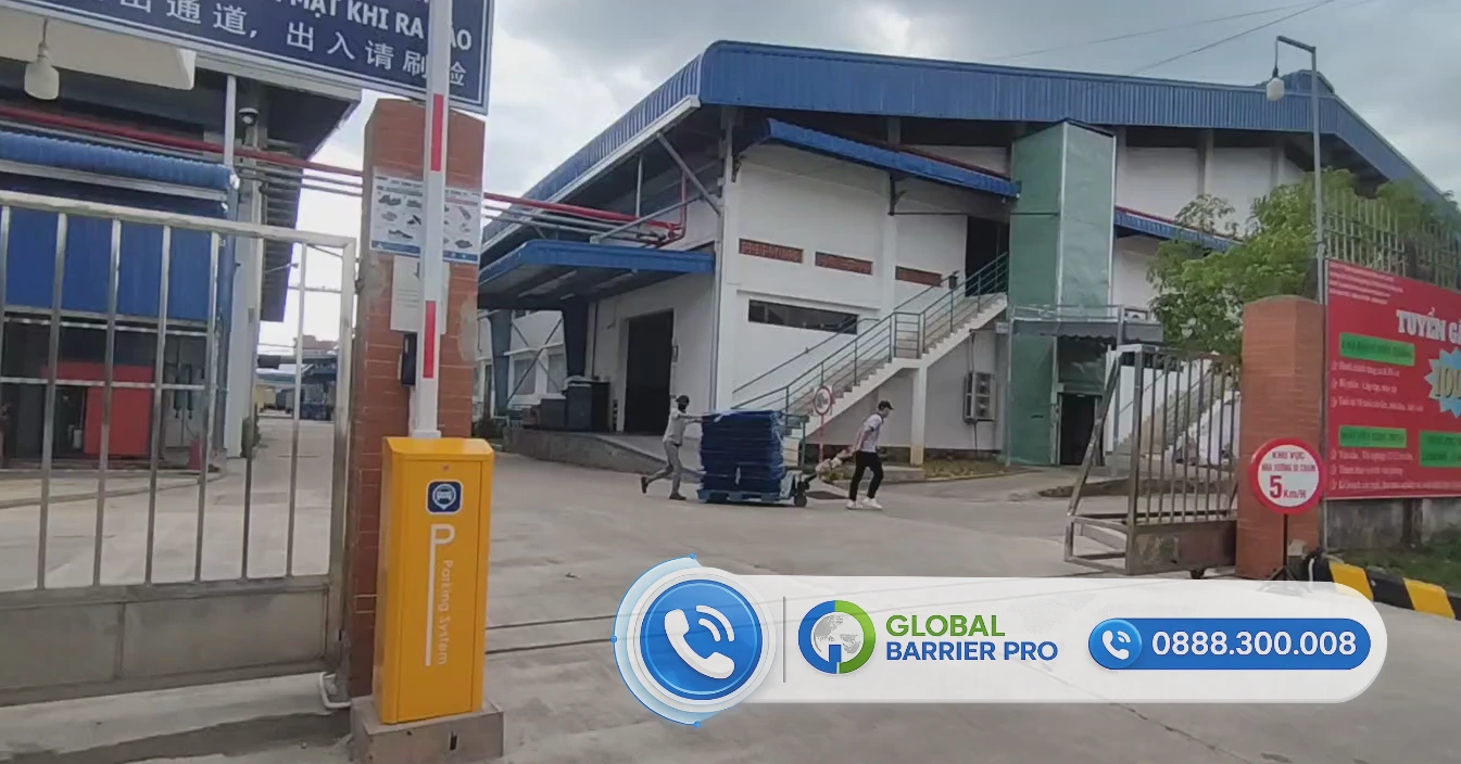 Cổng ra vào nhà xưởng công nghiệp với hệ thống rào chắn tự động và biển quảng cáo thương hiệu Global Barrier Pro