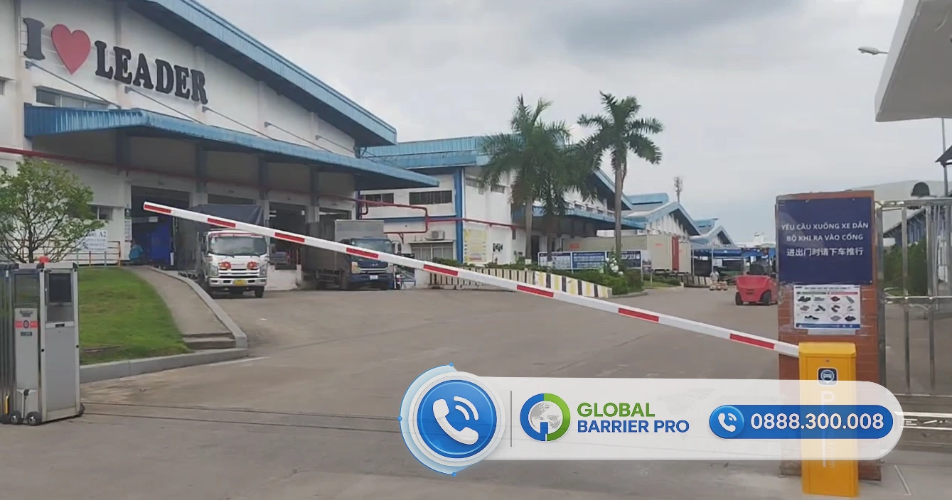 Cổng ra vào nhà xưởng công nghiệp với hệ thống rào chắn tự động và biển quảng cáo thương hiệu Global Barrier Pro